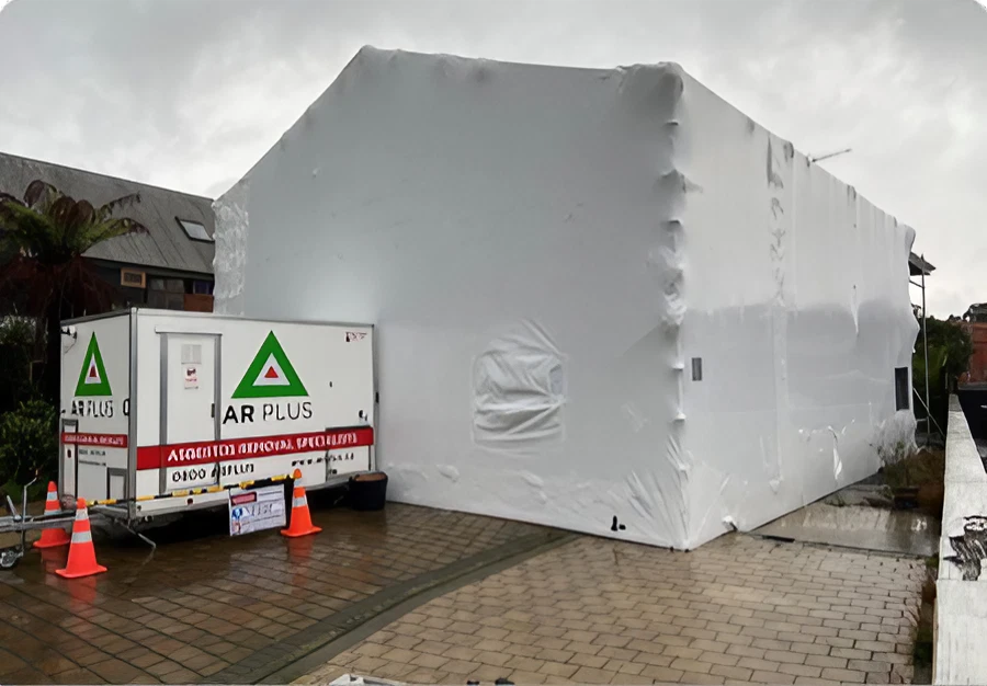 Image of a building wrapped in white plastic for asbestos control.